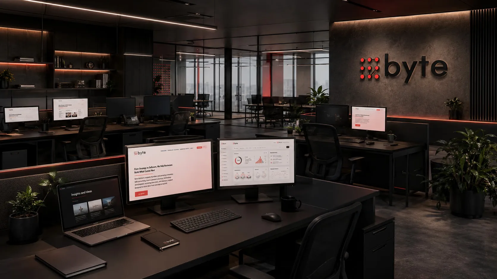 The Byte Advisory floor — desks running the firm’s own dashboards and site on screen, the byte wordmark backlit on the wall behind